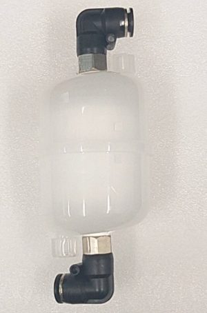 A white, cylindrical valve with black elbow connectors on each end, lying against a textured, light-colored surface, possibly made of foam or fabric.